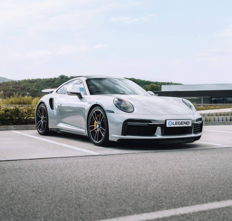 A Silver Porsche with a Legend license plate showcases its sleek design enhanced by premium Paint Protection Film